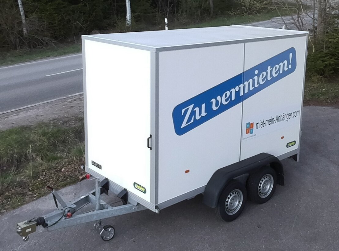 Weißer Kofferanhänger auf einem Hof